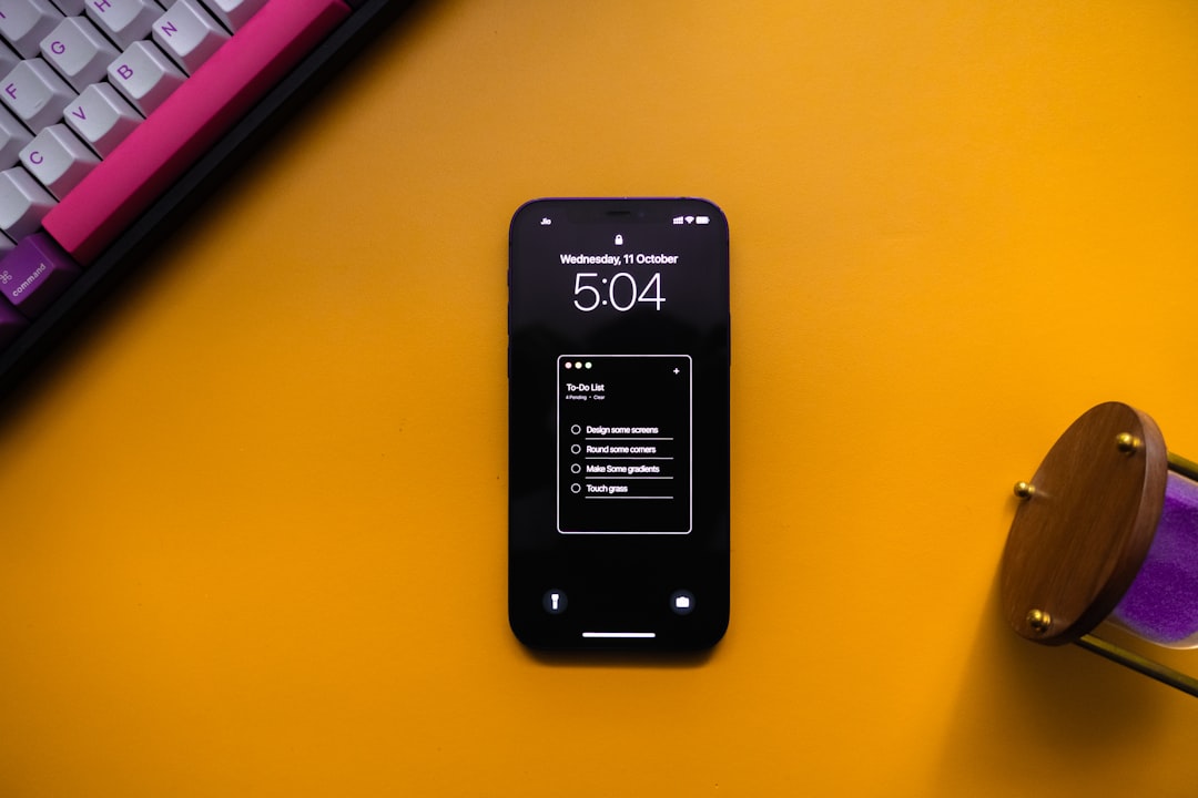 a-cell-phone-sitting-on-top-of-a-desk-next-to-a-keyboard-ytaa08ir7bm